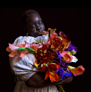 Low-light photo of a person holding a colorful bouquet of flowers.